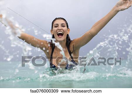 Young woman splashing water and laughing View Large Photo Image Stock Photo - Young woman splashing water and laughing. Fotosearch