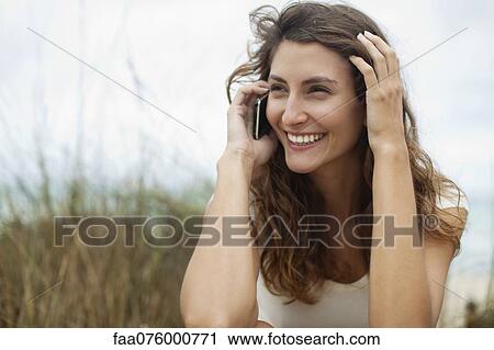 Stock Image - Young woman talking on cell phone, portrait. Fotosearch