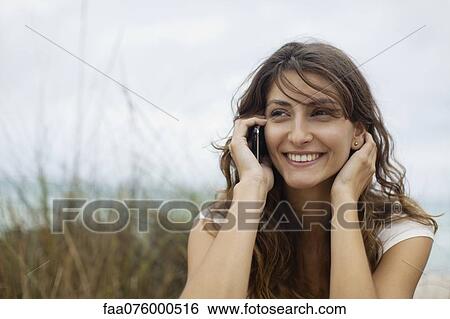 Stock Photograph - Young woman talking on cell phone, portrait. Fotosearch
