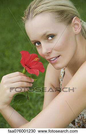Stock Image - Young woman with hibiscus flower, portrait. Fotosearch