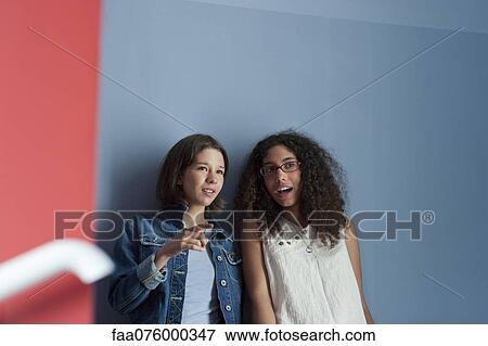 Stock Photo - Young women gossiping together in hall. Fotosearch