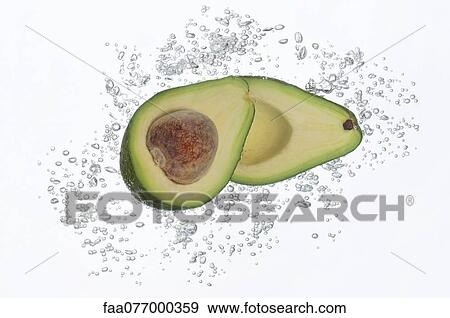 Stock Photo - Avocado halves submerged in sparkling water. Fotosearch