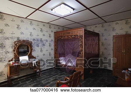 Stock Photograph - Bedroom decorated with ornately carved furniture and canopy bed. Fotosearch