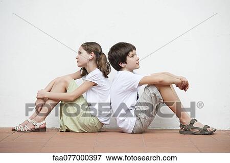 Stock Photo - Boy and girl sitting back to back listening to music together. Fotosearch