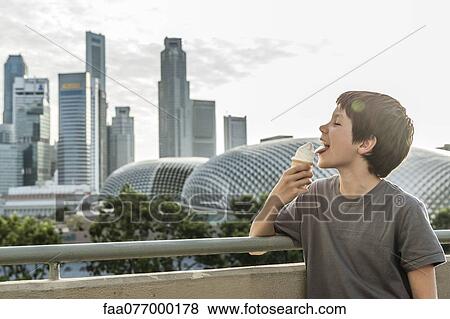 Boy eating ice cream cone, city skyline in background View Large Photo Image Stock Photo - Boy eating ice cream cone, city skyline in background. Fotosearch
