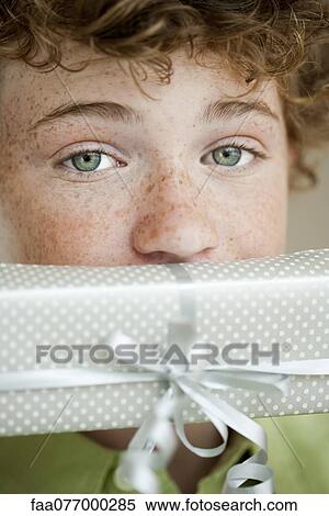Boy holding gift in front of mouth, portrait View Large Photo Image Stock Photography - Boy holding gift in front of mouth, portrait. Fotosearch