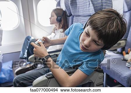 Picture - Boy leaning out of seat on airplane to look down aisle. Fotosearch