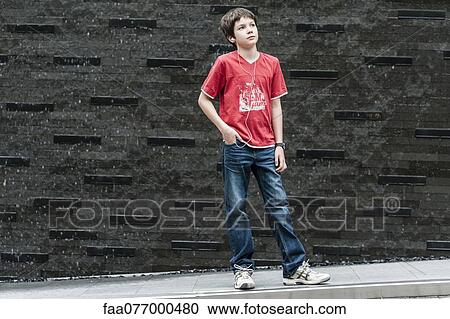 Stock Image - Boy listening to music with earphones, portrait. Fotosearch