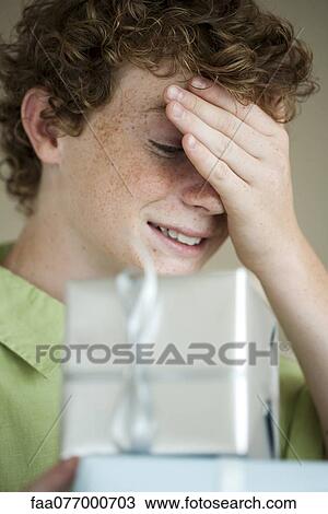 Stock Image - Boy peeking at wrapped gifts. Fotosearch