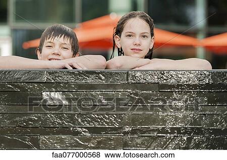 Stock Photo - Brother and sister leaning on edge of swimming pool side by side. Fotosearch