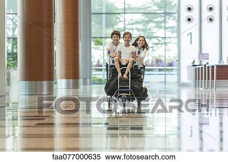 Brother and sister pushing younger sister on luggage cart in airport View Large Photo Image Stock Photography - Brother and sister pushing younger sister on luggage cart in airport. Fotosearch