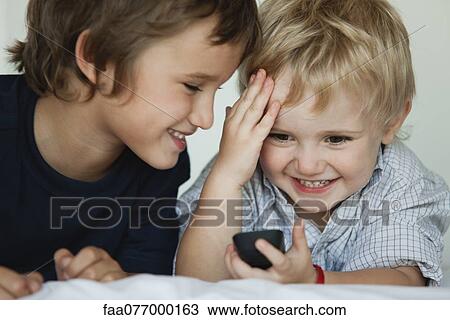 Stock Image - Brothers playing with cell phone. Fotosearch