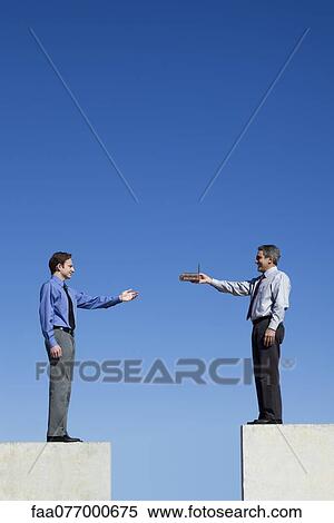 Stock Photography - Businessmen standing on platforms, one handing the other a tiny factory. Fotosearch