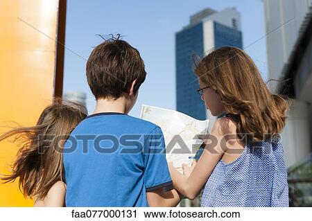 Stock Image - Children looking at map while sightseeing in city. Fotosearch