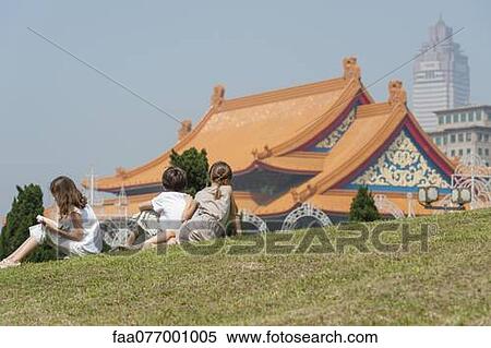 Stock Photography - Children sitting on grass overlooking National Concert Hall, Chiang Kai-Shek Memorial Hall, Taipei, Taiwan. Fotosearch