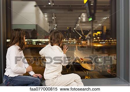 Stock Photography - Children watch from airport terminal window as flight crew prepare commercial airplane for boarding. Fotosearch