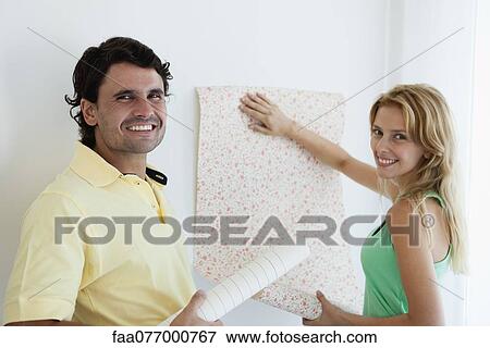 Stock Photo - Couple decorating new house with wallpaper. Fotosearch