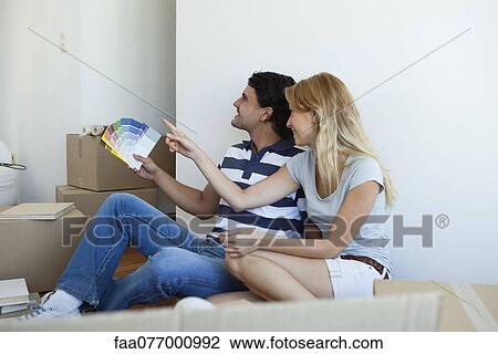 Stock Image - Couple discussing color swatches in new house. Fotosearch