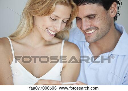 Stock Image - Couple looking at pregnancy test, smiling. Fotosearch