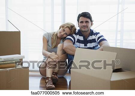 Stock Photography - Couple sitting in living room with cardboard boxes. Fotosearch
