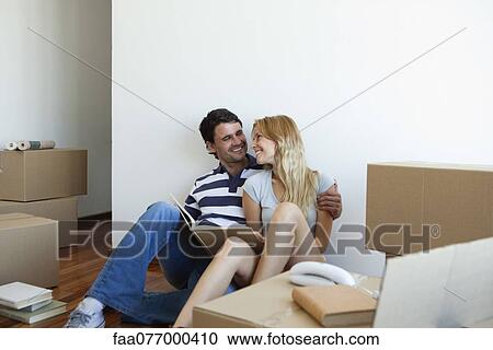 Stock Image - Couple unpacking cardboard boxes in new house. Fotosearch