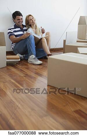 Stock Photo - Couple unpacking cardboard boxes in new house. Fotosearch