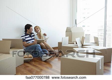 Couple unpacking cardboard boxes in new house View Large Photo Image Stock Photo - Couple unpacking cardboard boxes in new house. Fotosearch