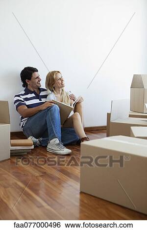 Stock Photograph - Couple unpacking cardboard boxes in new house. Fotosearch
