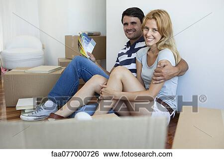 Stock Photograph - Couple unpacking in new house, man holding color swatches. Fotosearch