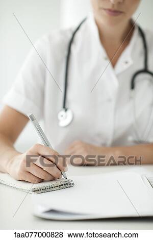 Stock Photo - Doctor writing notes on notepad, cropped. Fotosearch
