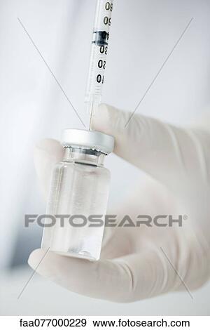Extracting liquid from vial with syringe View Large Photo Image Stock Photo - Extracting liquid from vial with syringe. Fotosearch