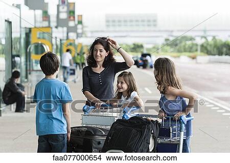 Picture - Family standing outside of airport with luggage. Fotosearch