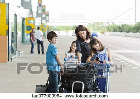 Picture - Family standing outside of airport with luggage. Fotosearch