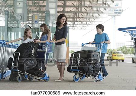 Stock Photograph - Family standing outside of airport with luggage. Fotosearch