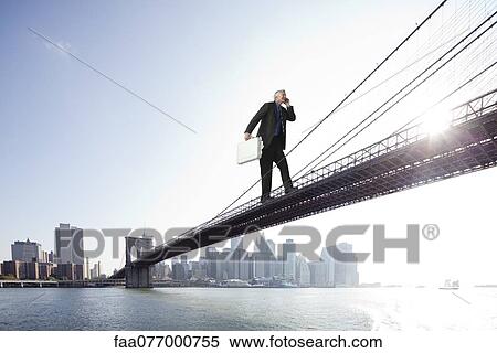 Giant businessman carrying briefcase stuffed with money across bridge View Large Photo Image Stock Photography - Giant businessman carrying briefcase stuffed with money across bridge. Fotosearch