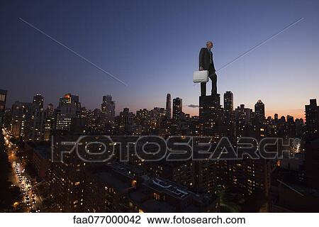 Giant businessman standing on top of skyscraper at dusk View Large Photo Image Stock Image - Giant businessman standing on top of skyscraper at dusk. Fotosearch