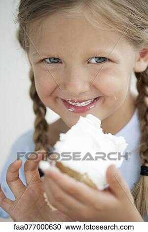 Stock Image - Girl eating cake, portrait. Fotosearch