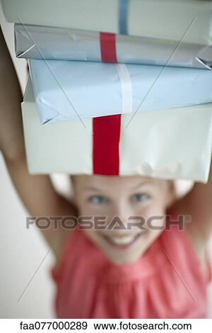 Stock Photo - Girl holding stack of gifts on head. Fotosearch