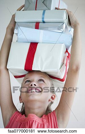 Girl holding stack of gifts on her head View Large Photo Image Stock Image - Girl holding stack of gifts on her head. Fotosearch