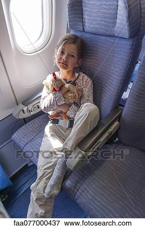 Stock Photo - Girl holding stuffed animal on airplane, portrait. Fotosearch
