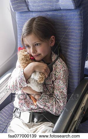 Stock Photo - Girl holding stuffed toy on airplane, portrait. Fotosearch