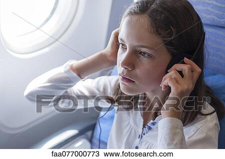 Girl listening to music on airplane with headphones View Large Photo Image Stock Image - Girl listening to music on airplane with headphones. Fotosearch