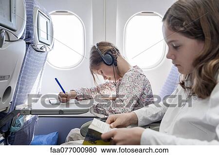 Stock Image - Girl listening to music on airplane with headphones. Fotosearch