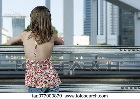 Stock Photo - Girl looking at city skyline, rear view. Fotosearch