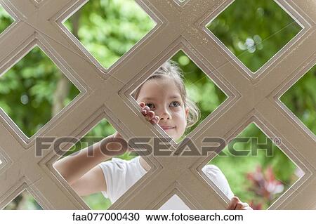 Girl looking through trellis View Large Photo Image Stock Image - Girl looking through trellis. Fotosearch