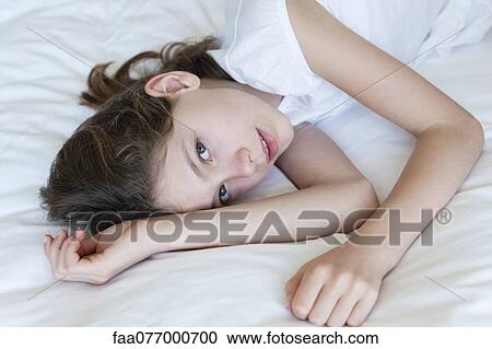 Stock Image - Girl lying on bed, portrait. Fotosearch
