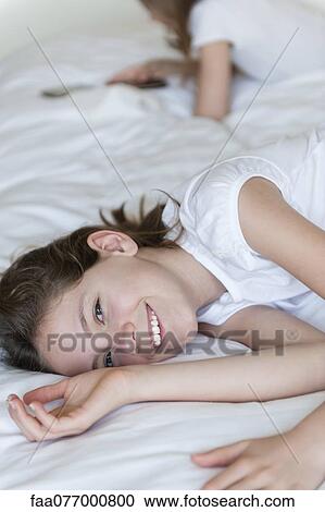 Girl lying on bed, smiling View Large Photo Image Stock Image - Girl lying on bed, smiling. Fotosearch