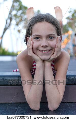 Stock Image - Girl lying on stomach, holding head, portrait. Fotosearch