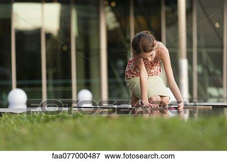 Girl picking up flower in water View Large Photo Image Stock Photo - Girl picking up flower in water. Fotosearch