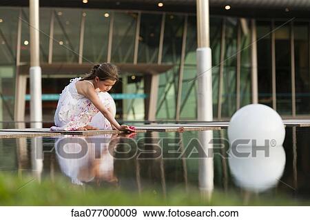 Girl placing flower on surface of water View Large Photo Image Stock Photo - Girl placing flower on surface of water. Fotosearch